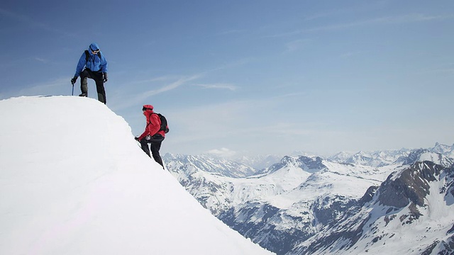 攀登者互相幫助到達白雪覆蓋的山峰