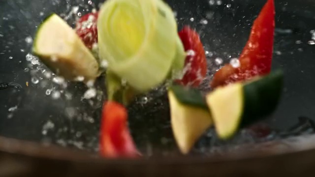 慢动作把蔬菜放进热锅里