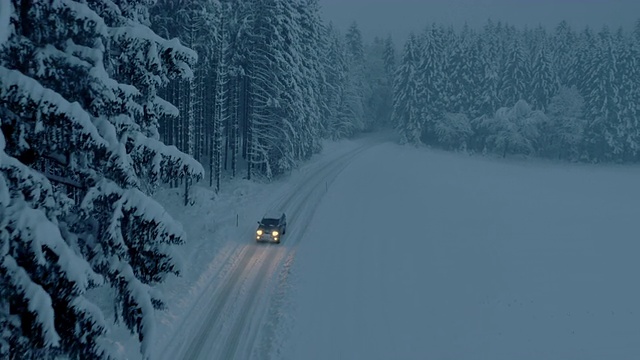 夜间，所有地形车辆行驶在被雪封的森林道路上