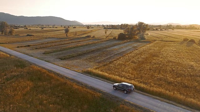 在夕阳下，在乡村道路上行驶的所有地形车辆