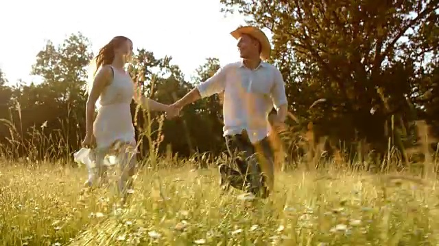 SLO MO TS夫妇牵着手跑过夏季草地