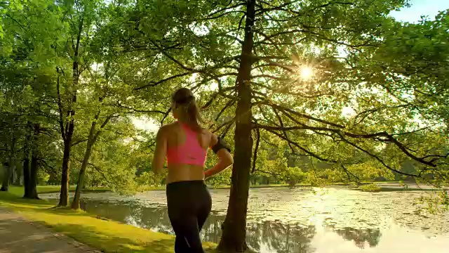 SLO MO TS女人在阳光下沿着湖跑
