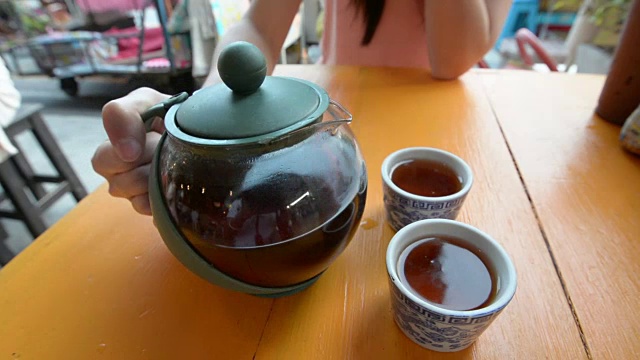 把茶倒在桌子上的杯子里