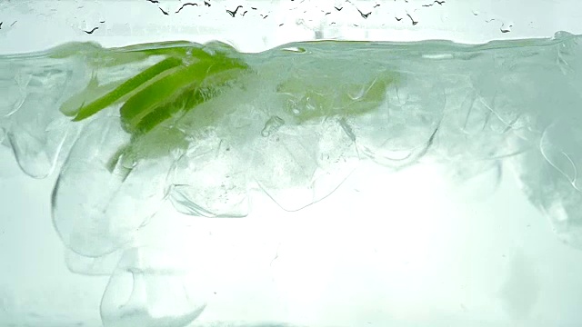 酸橙、柠檬和橙子片滴在冰水里。关闭了。缓慢的运动。