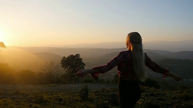 自由的女人向夕阳张开双臂旋转