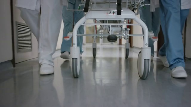 医疗队推着轮床走过医院走廊的双腿