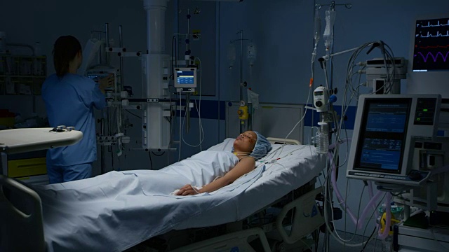 护士正在观察一位躺在重症监护室的女性病人
