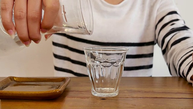 特写女子倒水到玻璃从水过滤壶饮用