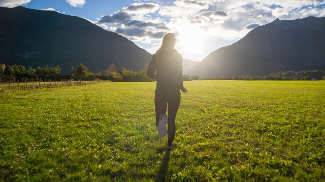 年轻女子在山腰奔向夕阳
