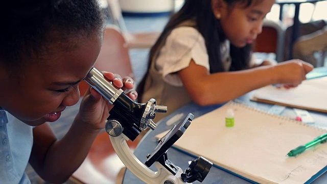 可爱的非裔美国STEM学校学生用显微镜检查东西