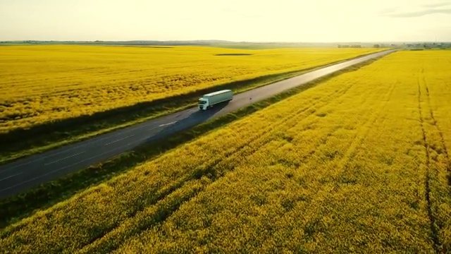 油菜籽田附近高速公路上卡車的鳥瞰圖