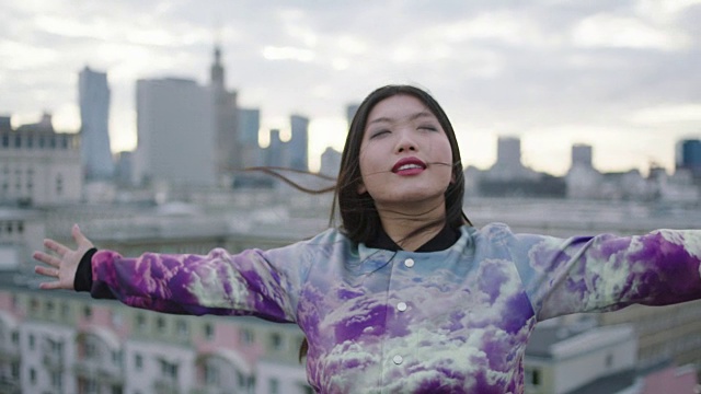 亚洲妇女在屋顶上打开双臂