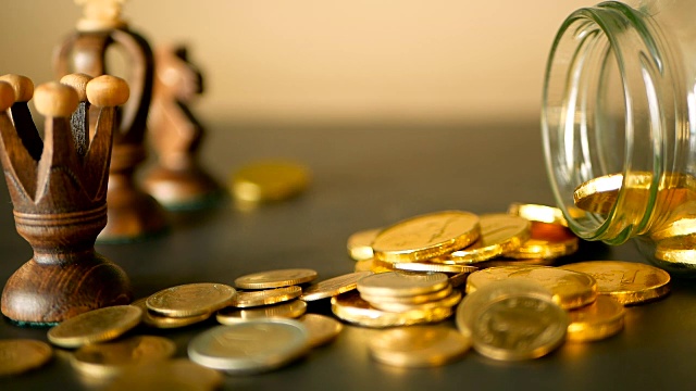 特写静物生活与黄金在黑色的桌子上，象棋和旋转便士。黄色的硬币从罐子里掉了出来。