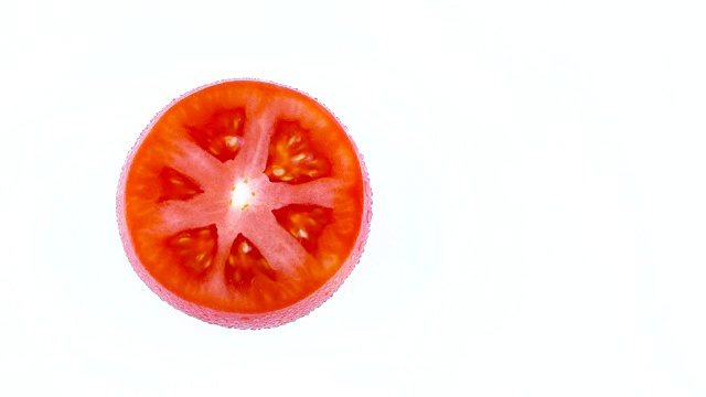 从上面俯视红色番茄横截面的半个框架。在白色背景上孤立的转盘上旋转。特写镜头。宏。