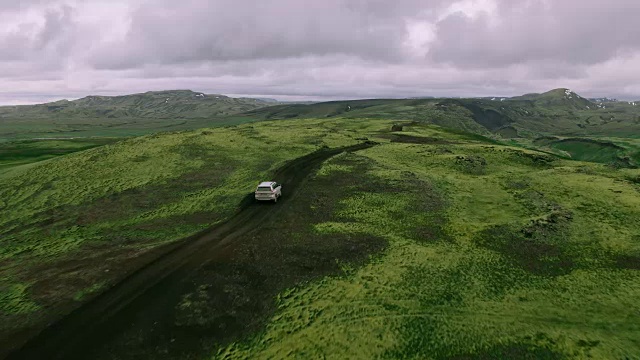 空中跟踪拍摄的银色4x4越野车行驶在山顶的山路