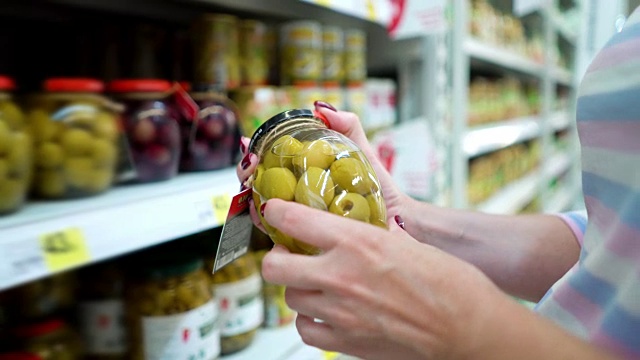 特写白人妇女手附近的商店货架选择腌制绿色橄榄在食品市场