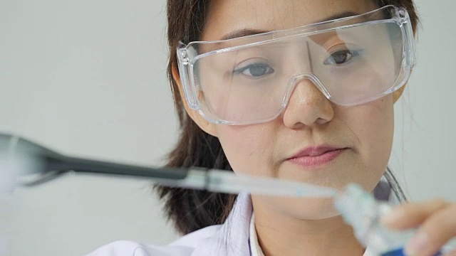 一个科学家用移液管分析有色液体，从试管中提取DNA和分子