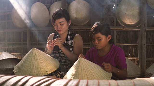 详情图-两名同胞越南工匠在老传统房子制作传统越南帽子的4k镜头低光场景，在Ap,Thoi,Phuoc村，Cantho省，越南，传统艺术家的概念