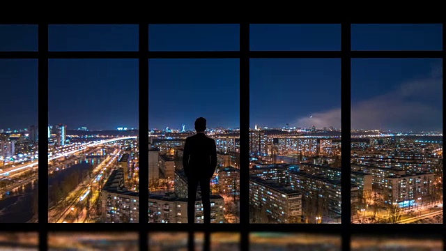 详情图-这个男人站在窗户旁边，背景是夜晚的大都市。时间流逝