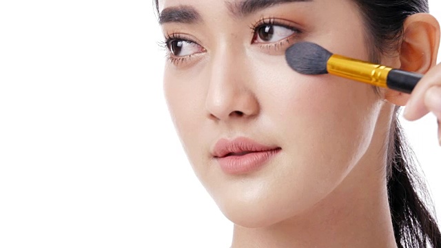 詳情圖-亞洲美麗的女人使用刷子化妝她的臉在白色的背景。人具有美容、化妝、保健的理念。