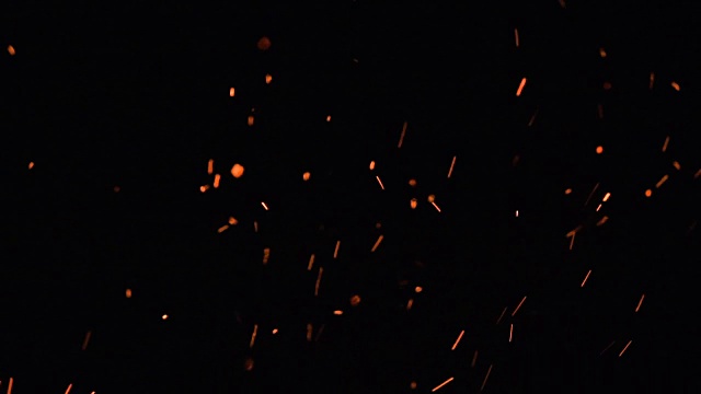 高速拍摄的火焰和发光的灰烬颗粒在黑色的背景