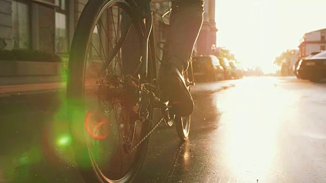 詳情圖-近距離拍攝的英俊的年輕人駕駛他的自行車在街道上的城市中心在日出，慢動(dòng)作