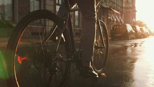 詳情圖-近距離拍攝的英俊的年輕人駕駛他的自行車在街道上的城市中心在日出，慢動(dòng)作