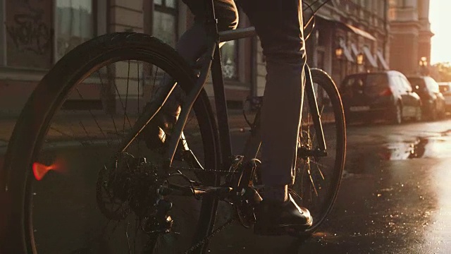 詳情圖-近距離拍攝的英俊的年輕人駕駛他的自行車在街道上的城市中心在日出，慢動(dòng)作