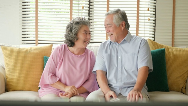 快乐的老两口一起看电视。人们以放松、养老、退休、高级生活方式为家庭观念。