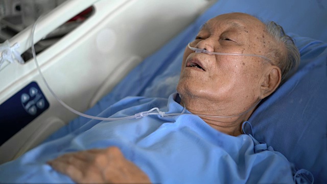 年长的亚洲男性病人在医院的床上呼吸困难