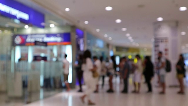 模糊或散焦排队使用银行机器或ATM(自动柜员机)存款、取款和转账的人们的背景