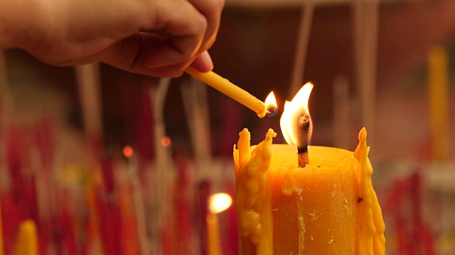祈祷者点燃香烛，蜡烛上放一根蜡烛火，靠近。