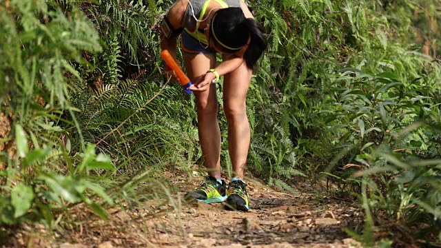 健身亚洲女性越野跑步者在森林山越野跑步前涂抹防晒霜尖叫乳液