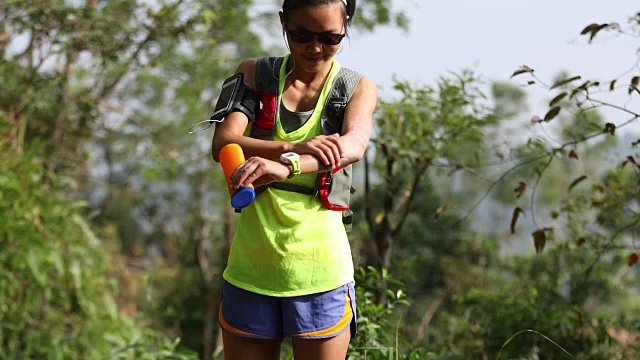 健身亚洲女性越野跑步者在森林山越野跑步前涂抹防晒霜尖叫乳液