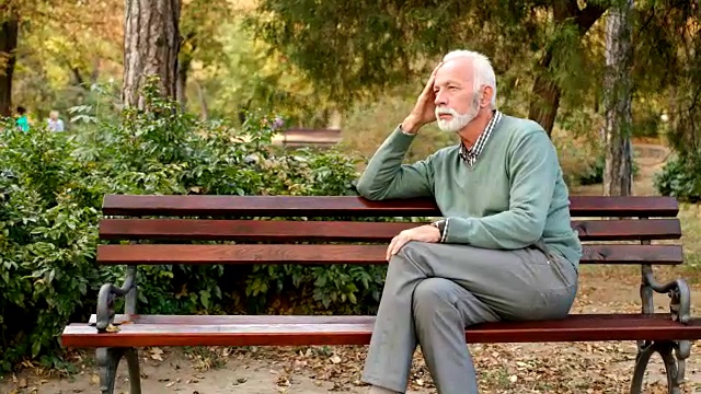 一个老人独自坐在公园的长椅上