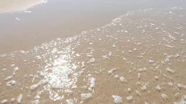 浅浅的波光粼粼的海水在海滩上缓慢地蔓延