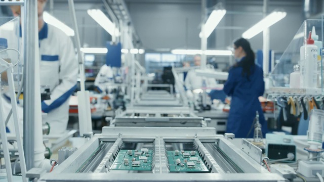 當它在裝配線上移動時，電子廠工人用手組裝電路板的時間流逝。高科技工廠設(shè)施。