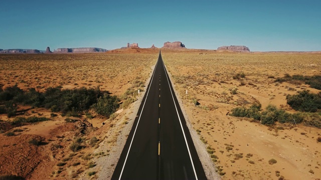 詳情圖-無人機向后飛行在紀念碑谷標志性的空砂巖沙漠道路，亞利桑那州與巨大的懸崖山脈。