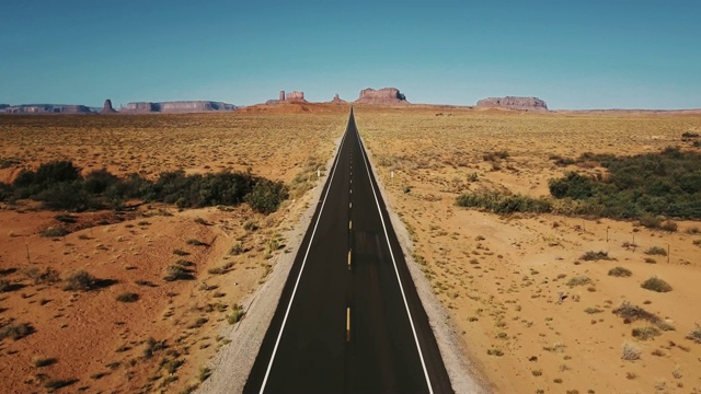 詳情圖-無人機向后飛行在紀念碑谷標志性的空砂巖沙漠道路，亞利桑那州與巨大的懸崖山脈。