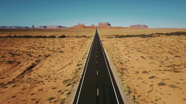 詳情圖-無人機向后飛行在紀念碑谷標志性的空砂巖沙漠道路，亞利桑那州與巨大的懸崖山脈。