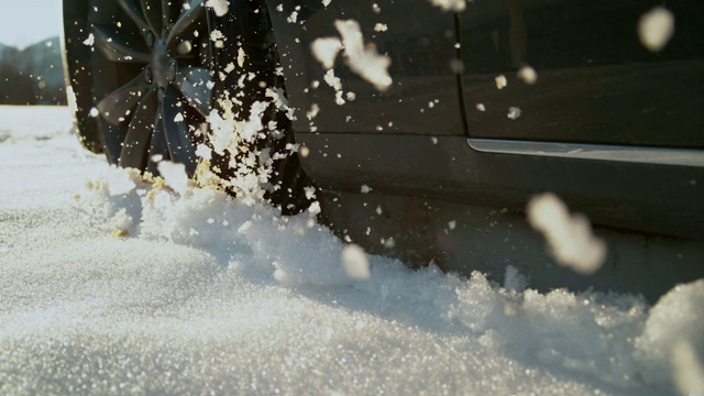 慢镜头:在阳光明媚的日子里，一辆汽车驶离公路，吐出了几块湿雪。