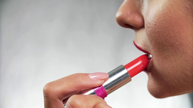 红色的口红。女人用口红丰满性感的嘴唇特写
