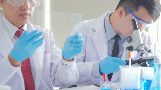 在生命科学实验室工作的卫生保健研究人员。年轻男性研究科学家在实验室准备和分析显微镜载玻片。科学实验室