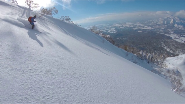 無人機(jī):自由式滑雪者在風(fēng)景優(yōu)美的山上騎行時(shí)撕碎積雪。