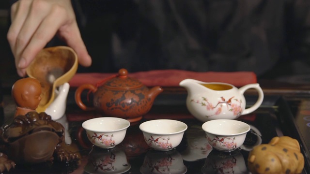 茶道。师傅将茶倒在白色杯子上