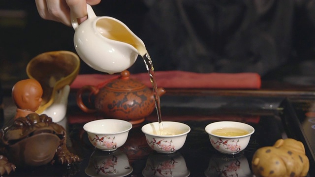 茶道。师傅将茶倒在白色杯子上