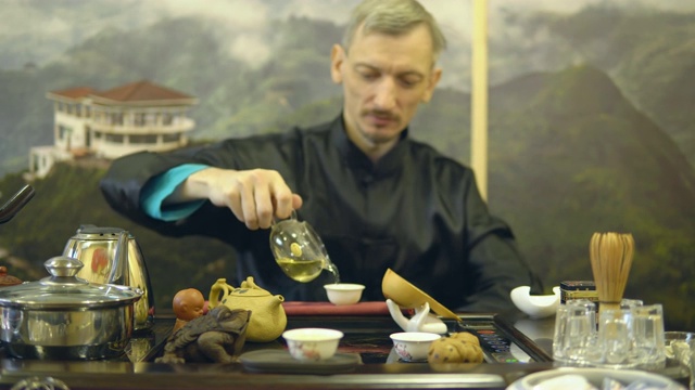 茶道。师傅将绿茶从玻璃茶壶中倒进白杯子里