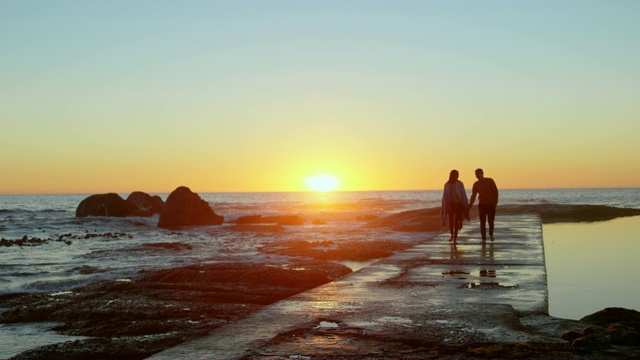 一对夫妇手牵手走在码头在夕阳4k