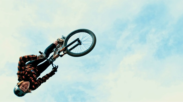 MS Young man在多云的天空下翻转BMX自行车