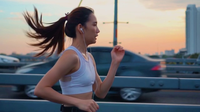 日落，年轻女子慢跑过桥的慢镜头